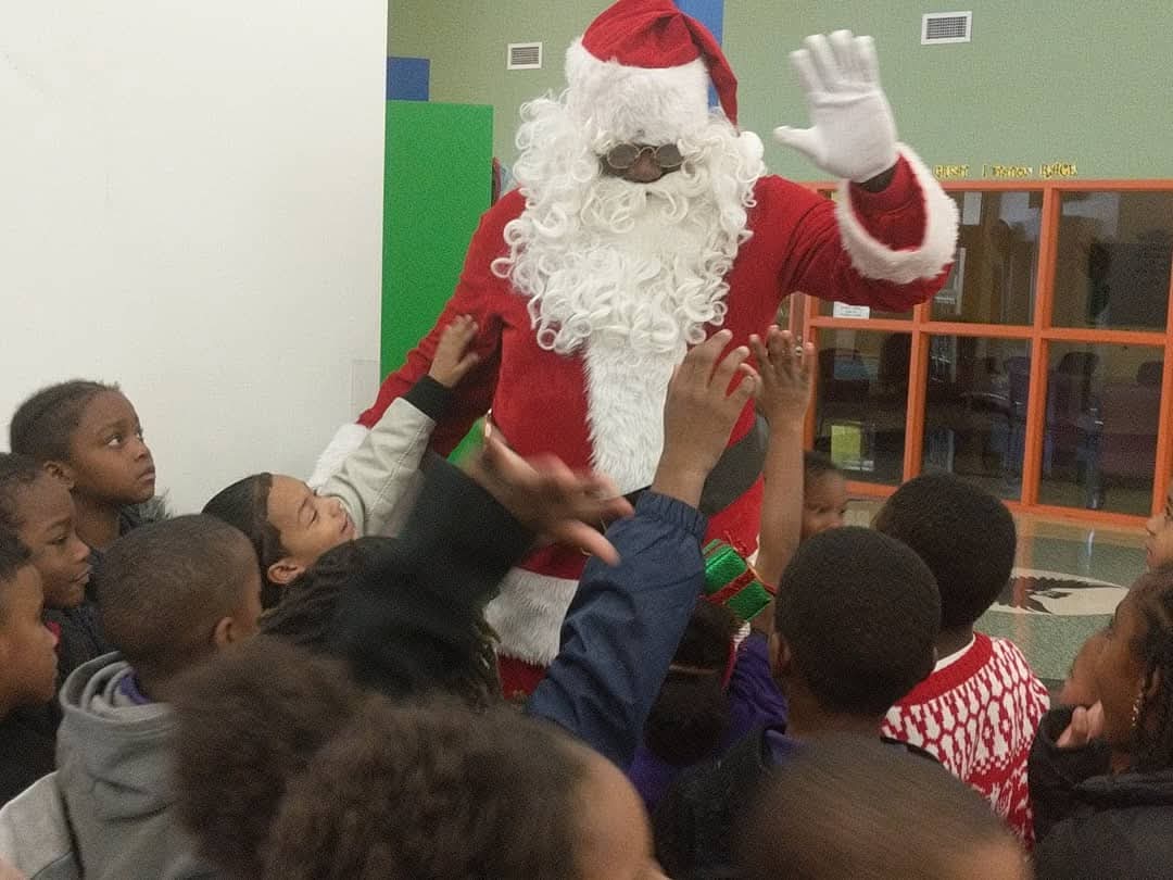 Children reaching up to Santa at the annual Truly MAD holiday giveaway